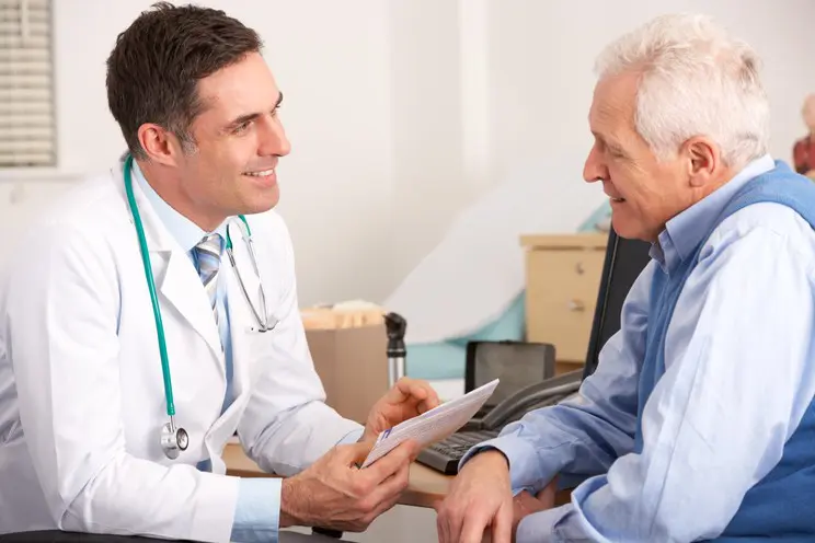 A doctor and an older man are talking to each other.