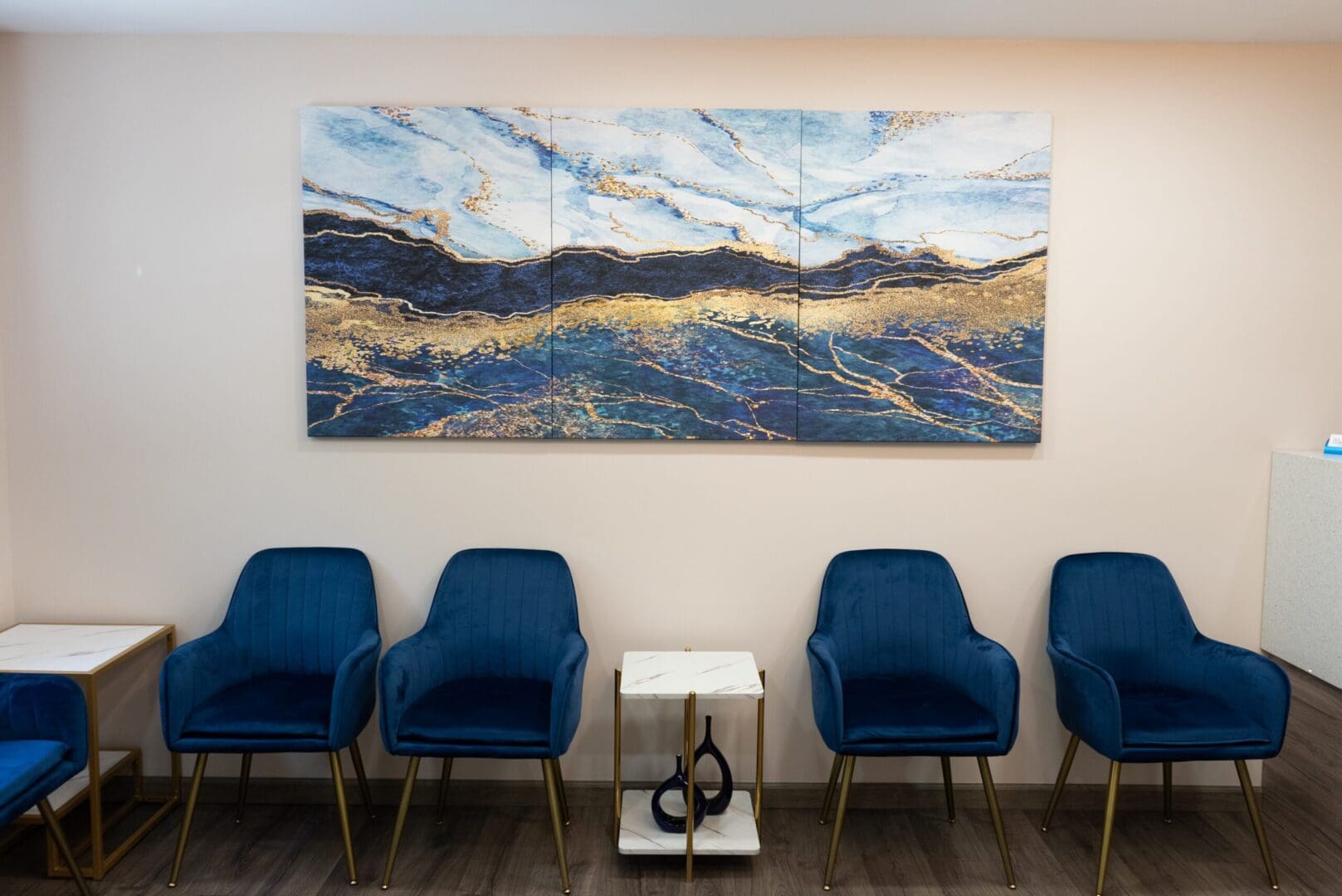 A group of blue chairs in front of a painting.