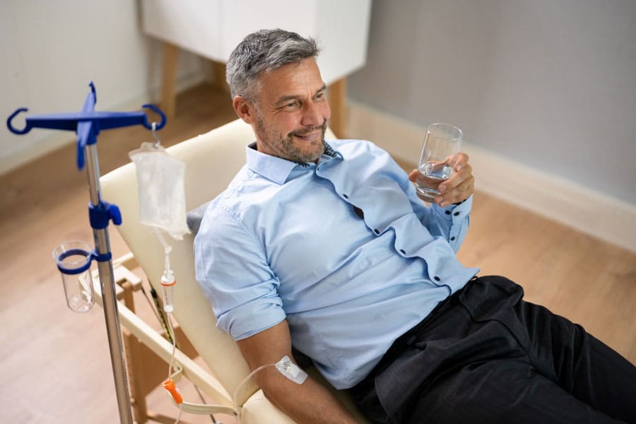 A man sitting in a chair holding a glass of water.