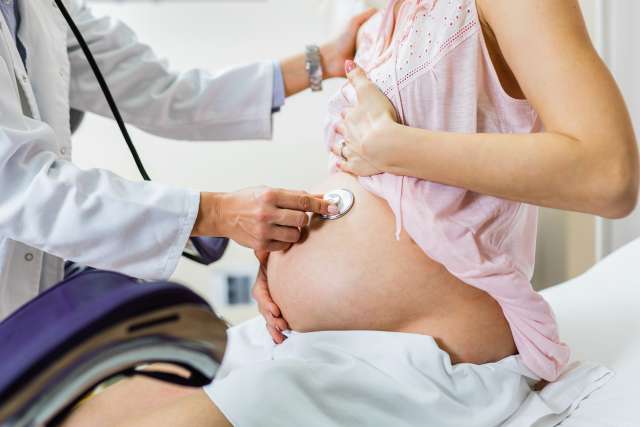 A doctor is examining the pregnant woman 's belly.